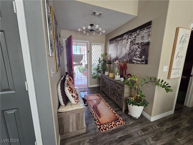 foyer entrance featuring a chandelier, visible vents, baseboards, and wood finished floors