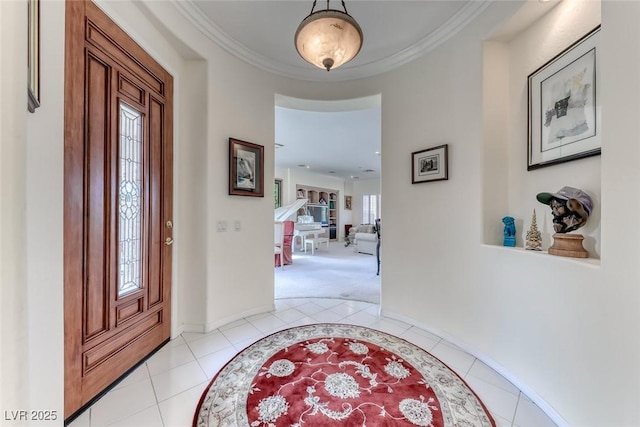 foyer featuring light tile patterned floors, baseboards, and crown molding