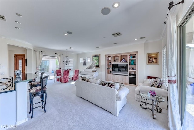 living room with built in shelves, a notable chandelier, ornamental molding, recessed lighting, and carpet flooring