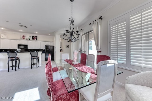 dining room with a chandelier, visible vents, light colored carpet, and ornamental molding