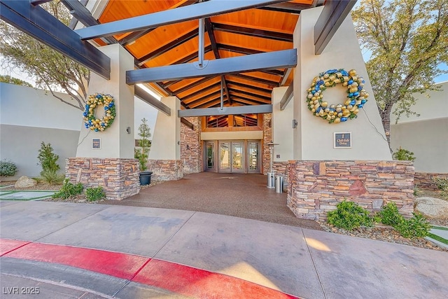 entrance to property featuring french doors, stucco siding, and stone siding