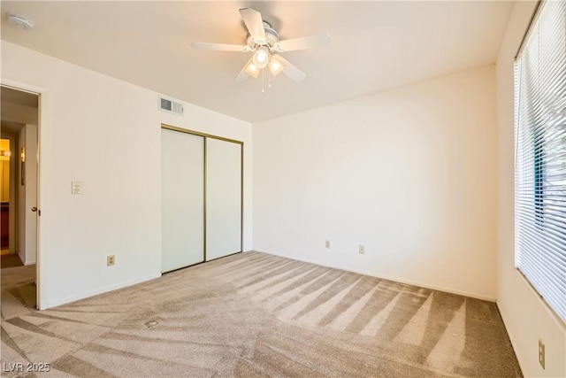 unfurnished bedroom with a closet, carpet floors, visible vents, and a ceiling fan