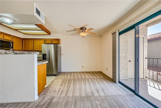 kitchen featuring visible vents, ceiling fan, brown cabinetry, stainless steel appliances, and light carpet