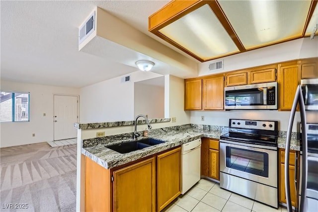 kitchen featuring stainless steel appliances, visible vents, a sink, and brown cabinets