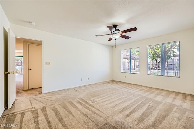 unfurnished room featuring ceiling fan, light colored carpet, and baseboards