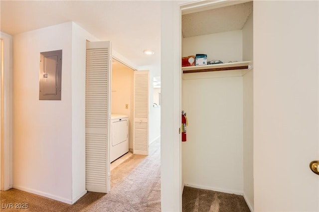 hallway with washer / clothes dryer, light colored carpet, baseboards, and electric panel