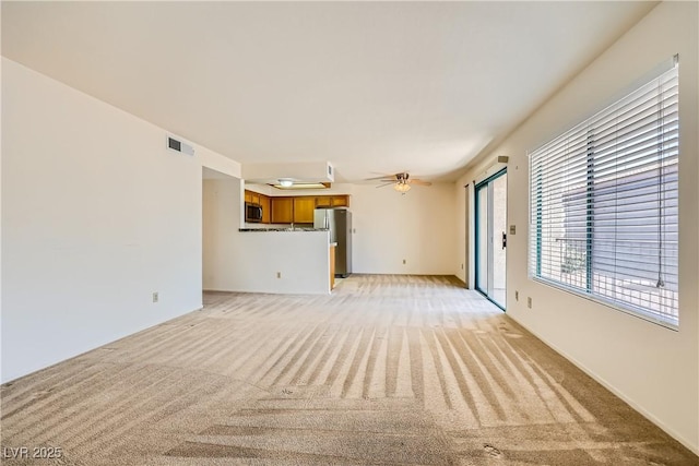 unfurnished living room with light carpet, visible vents, and ceiling fan