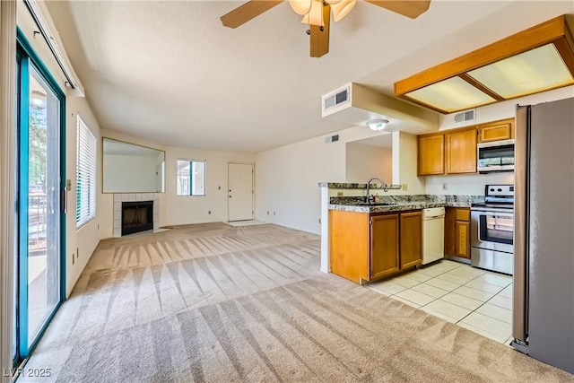 kitchen featuring stainless steel appliances, visible vents, brown cabinets, and light carpet