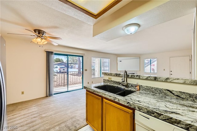 kitchen featuring a sink, brown cabinetry, plenty of natural light, and dishwasher