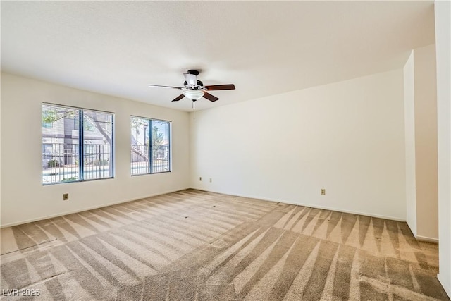 unfurnished room featuring light carpet, baseboards, and a ceiling fan