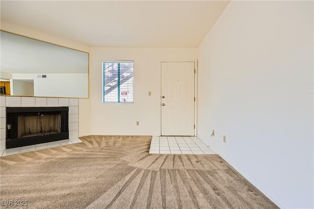 unfurnished living room featuring a tiled fireplace and carpet flooring