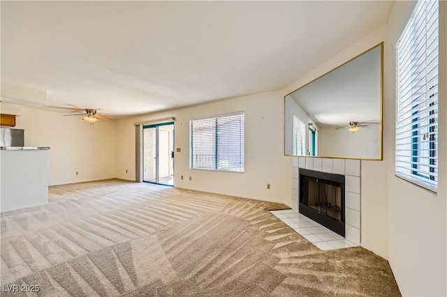 unfurnished living room with light carpet, a tile fireplace, and ceiling fan
