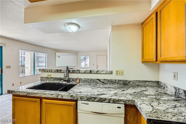 kitchen featuring a sink, brown cabinetry, dishwasher, and stove