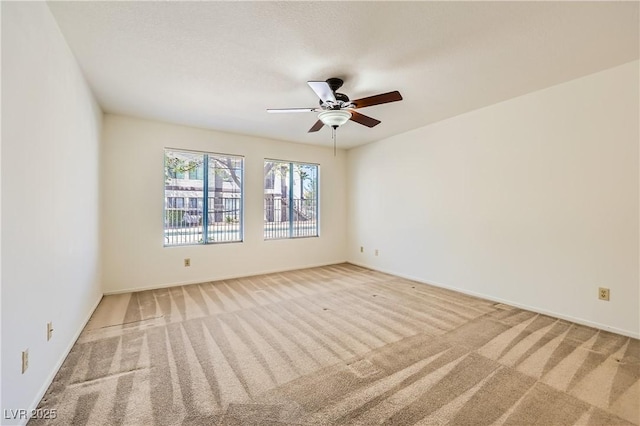 empty room featuring ceiling fan, carpet, and baseboards