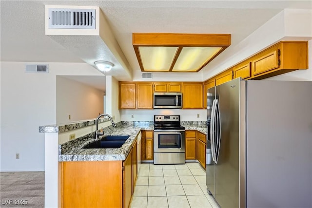 kitchen with a sink, visible vents, brown cabinetry, and appliances with stainless steel finishes