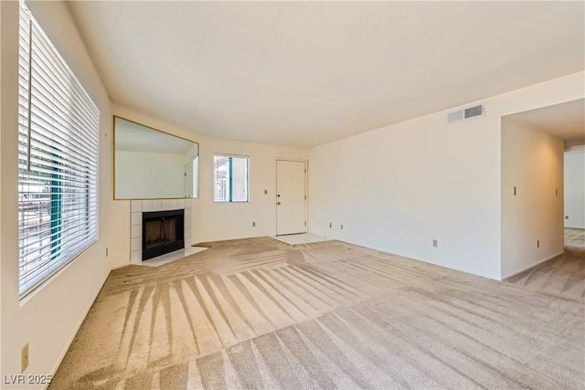 unfurnished living room featuring carpet flooring, a tiled fireplace, and visible vents