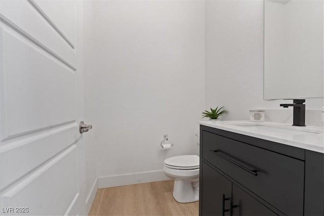 bathroom with vanity, baseboards, toilet, and wood finished floors