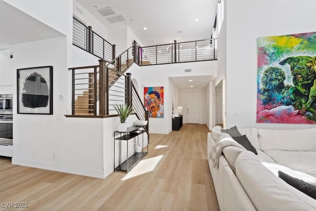 interior space featuring visible vents, a high ceiling, wood finished floors, and stairs