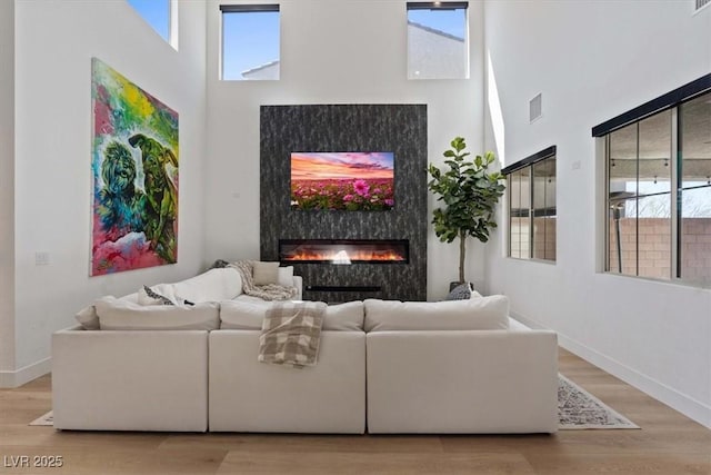 living room with visible vents, baseboards, light wood-type flooring, and a premium fireplace