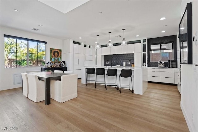 kitchen featuring modern cabinets, tasteful backsplash, light wood-type flooring, white cabinetry, and a spacious island
