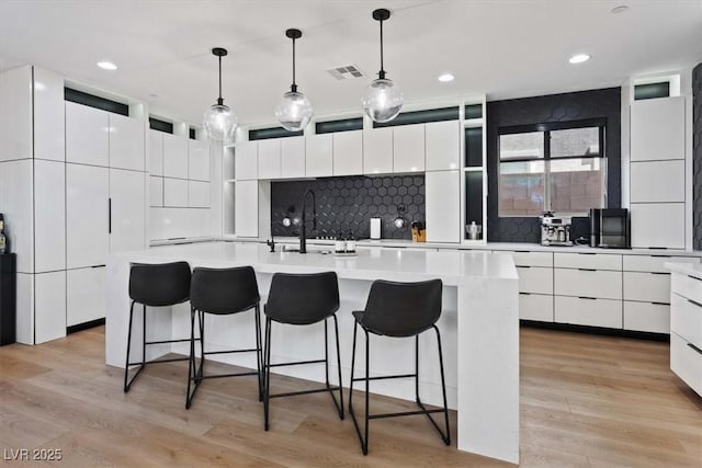 kitchen with a kitchen breakfast bar, visible vents, modern cabinets, and light wood finished floors