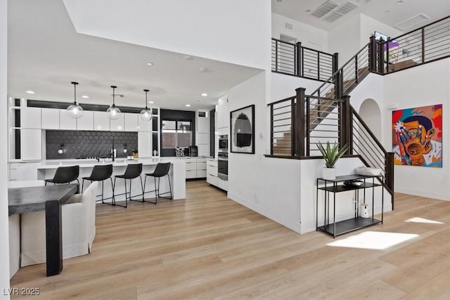 interior space with visible vents, baseboards, recessed lighting, stairway, and light wood-style flooring