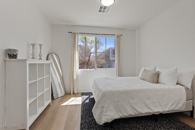 bedroom featuring visible vents and wood finished floors