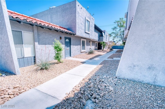 view of side of home with stucco siding and a tile roof