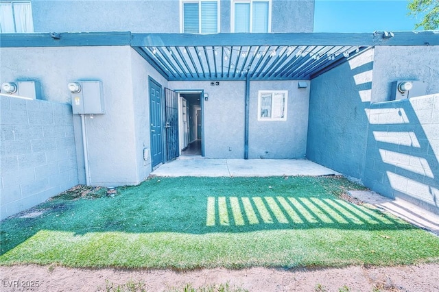 view of exterior entry with stucco siding, fence, and a lawn