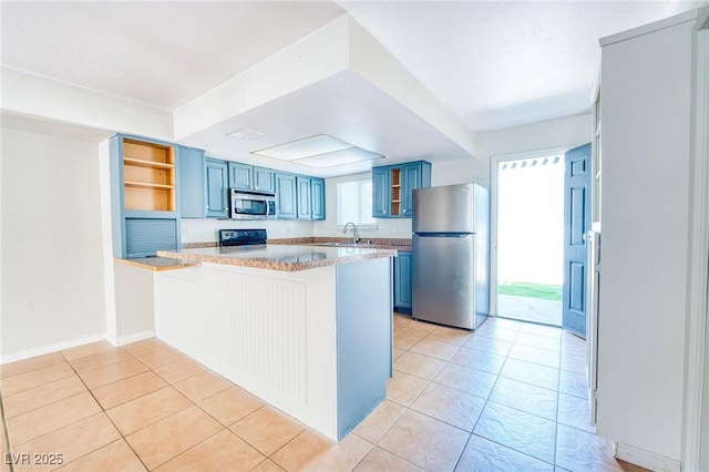 kitchen featuring a peninsula, blue cabinetry, open shelves, a sink, and stainless steel appliances