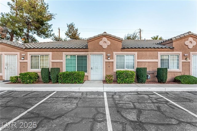 view of front of house with uncovered parking, stucco siding, and a tile roof