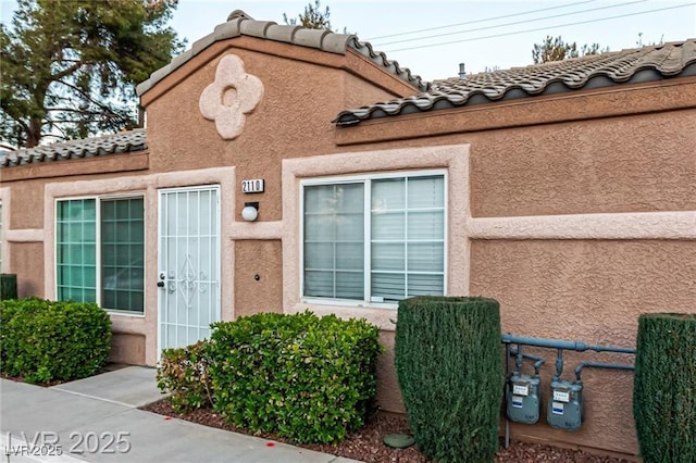 entrance to property with a tiled roof and stucco siding