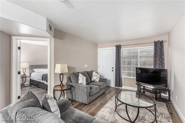 living area featuring visible vents, baseboards, ceiling fan, and wood finished floors