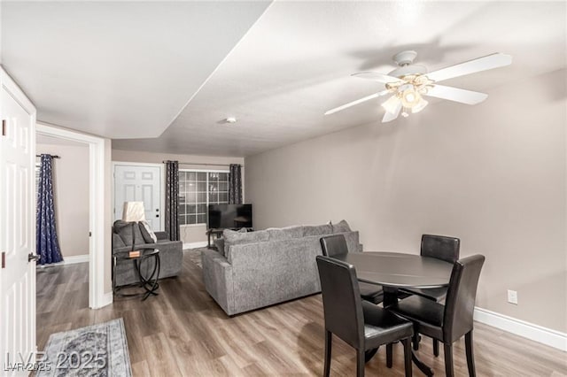 dining space with light wood-type flooring, baseboards, and a ceiling fan