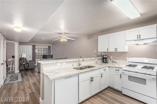 kitchen featuring white appliances, a peninsula, white cabinetry, under cabinet range hood, and a sink