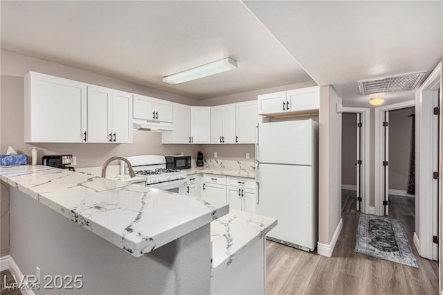 kitchen with visible vents, white appliances, a peninsula, under cabinet range hood, and white cabinetry