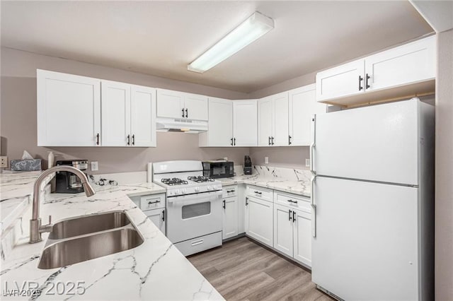 kitchen with white appliances, light stone countertops, white cabinets, under cabinet range hood, and a sink