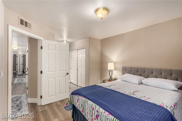 bedroom featuring wood finished floors, a closet, and visible vents