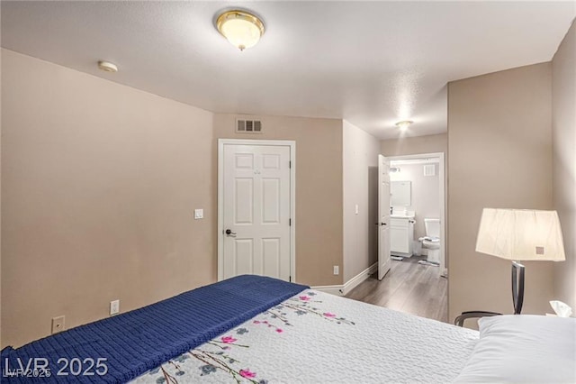 unfurnished bedroom featuring visible vents, baseboards, light wood finished floors, and connected bathroom