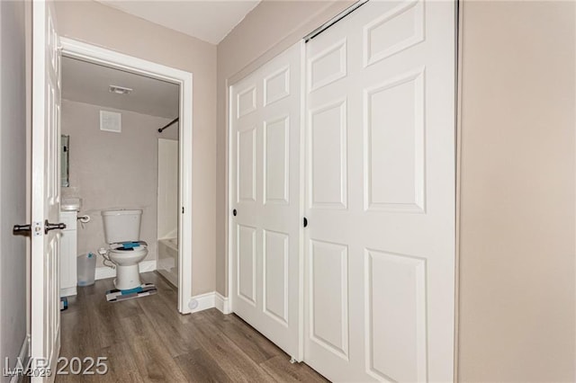interior space with baseboards, shower / washtub combination, toilet, visible vents, and wood finished floors