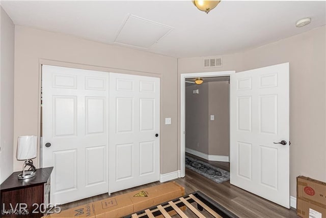 bedroom featuring visible vents, baseboards, a closet, dark wood finished floors, and attic access