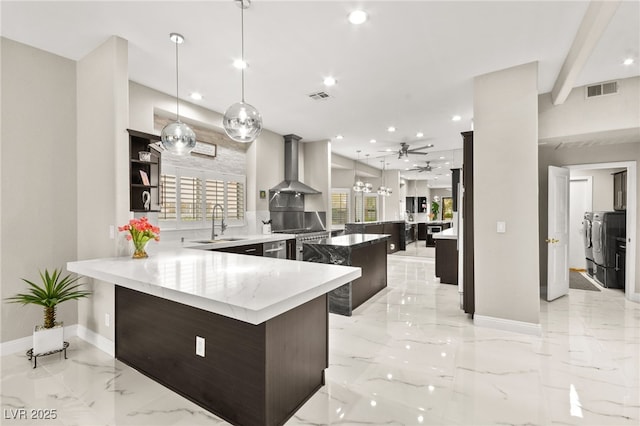 2608 Sun Reef Rd, Las Vegas, NV 89128 - kitchen with wall chimney exhaust hood, a peninsula, visible vents, marble finish floor, and washing machine and dryer