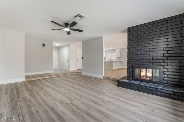 unfurnished living room with baseboards, visible vents, light wood-type flooring, and a ceiling fan