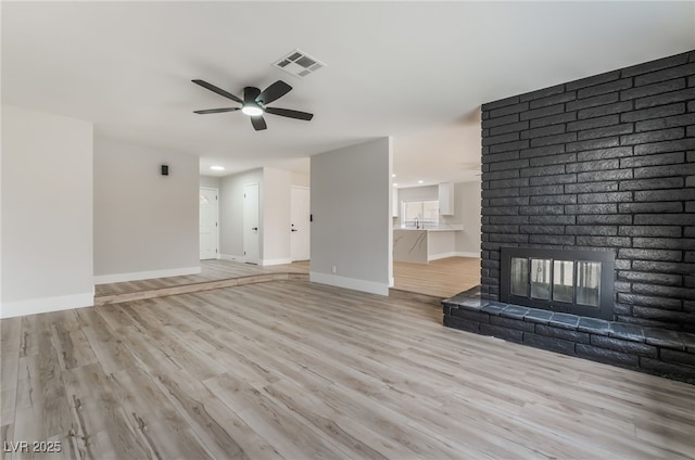 unfurnished living room featuring light wood-style floors, baseboards, a ceiling fan, and visible vents