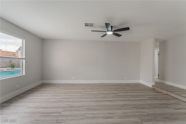 empty room with light wood-style floors, visible vents, baseboards, and a ceiling fan