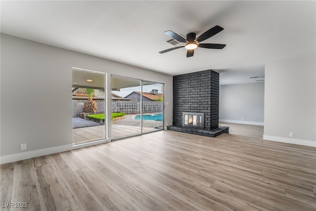 unfurnished living room with wood finished floors, a fireplace, a ceiling fan, and baseboards