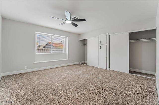 unfurnished bedroom featuring carpet, a ceiling fan, two closets, and baseboards