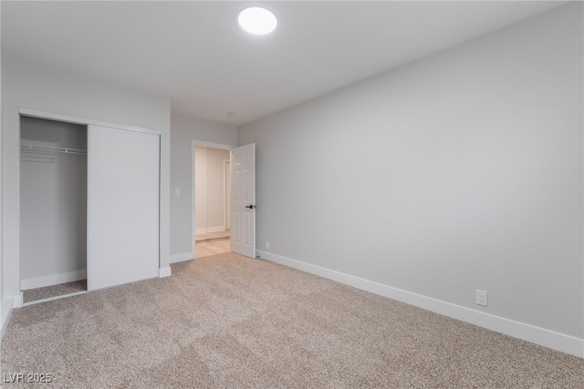 unfurnished bedroom with light carpet, a closet, and baseboards