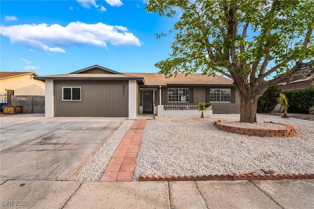 single story home with concrete driveway, brick siding, and fence