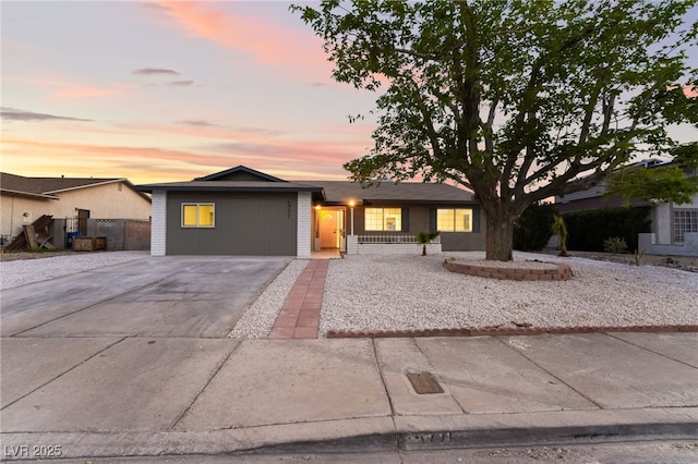 view of front facade with concrete driveway, fence, and brick siding